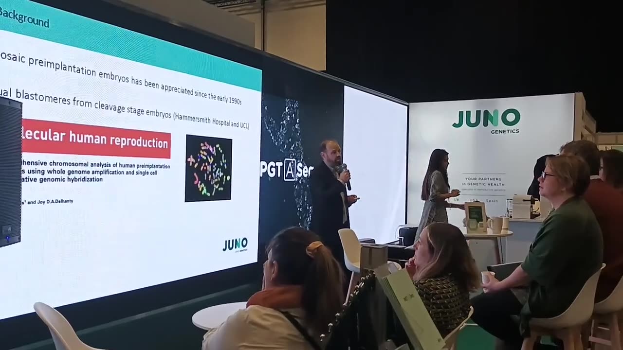 Stand de Juno Genetics con moqueta verde y paneles retroiluminados