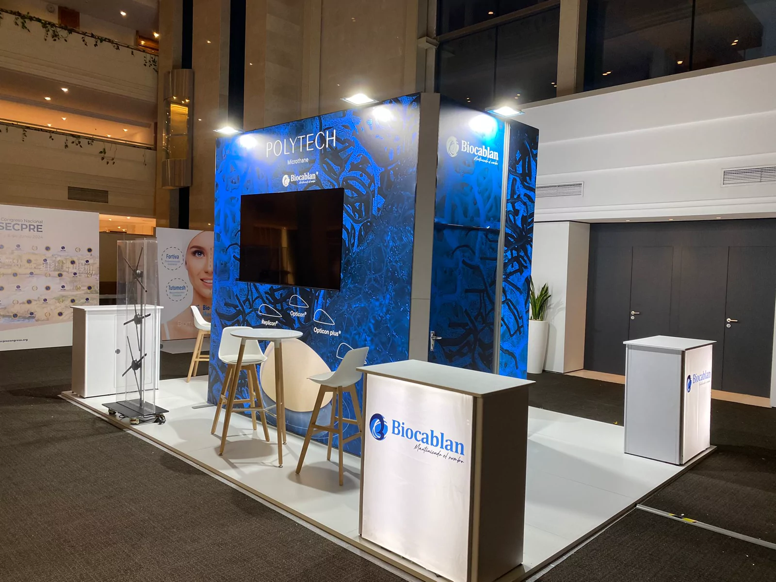 Stand de Biocablan y Polytech con gráfica azul, pantalla y mostradores iluminados