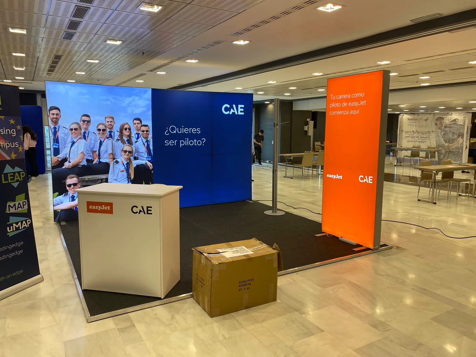 Stand de CAE y easyJet con paneles retroiluminados, mostrador y tótem naranja