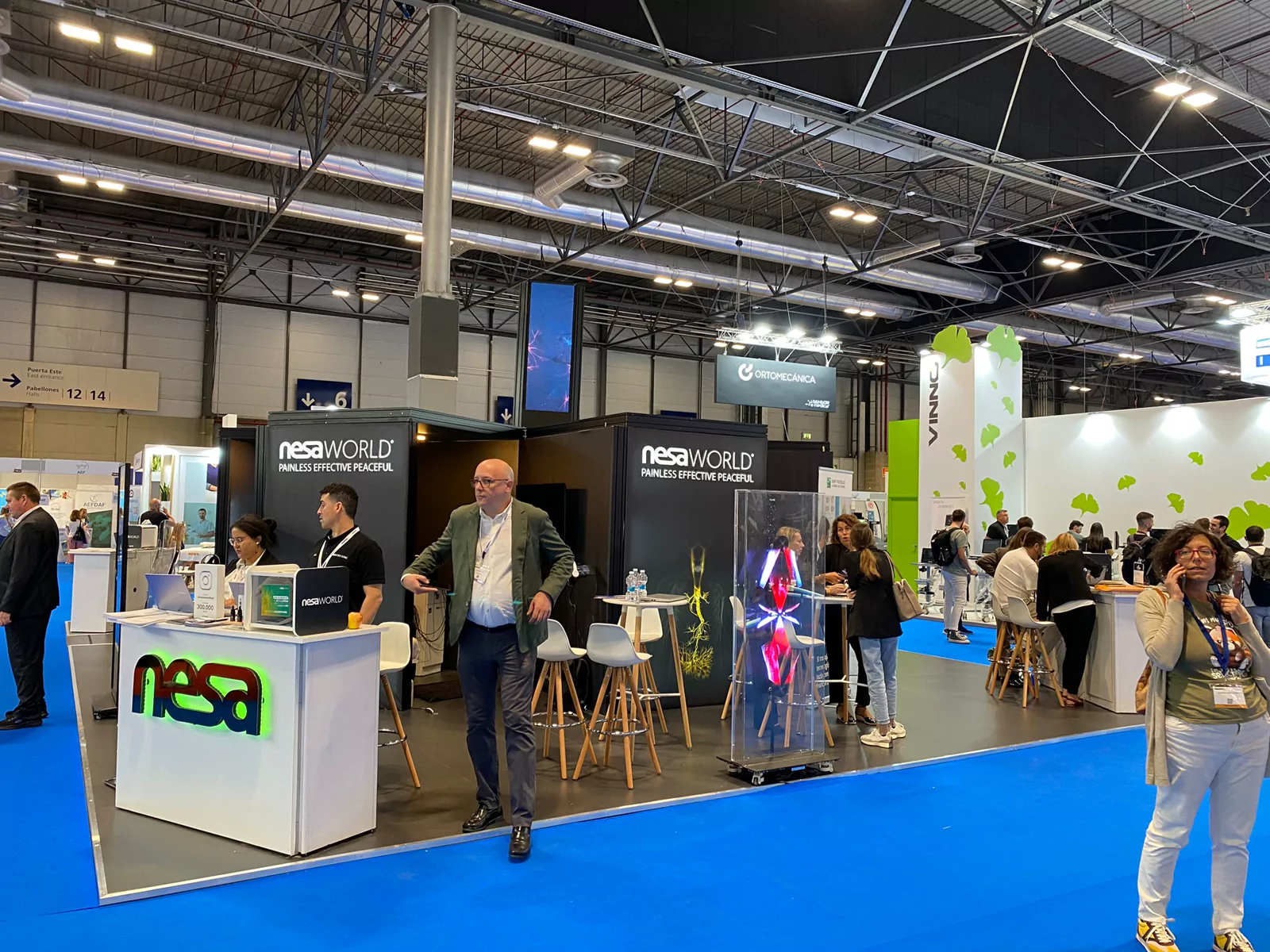 Stand de NesaWorld con recepción iluminada y holograma de gran formato