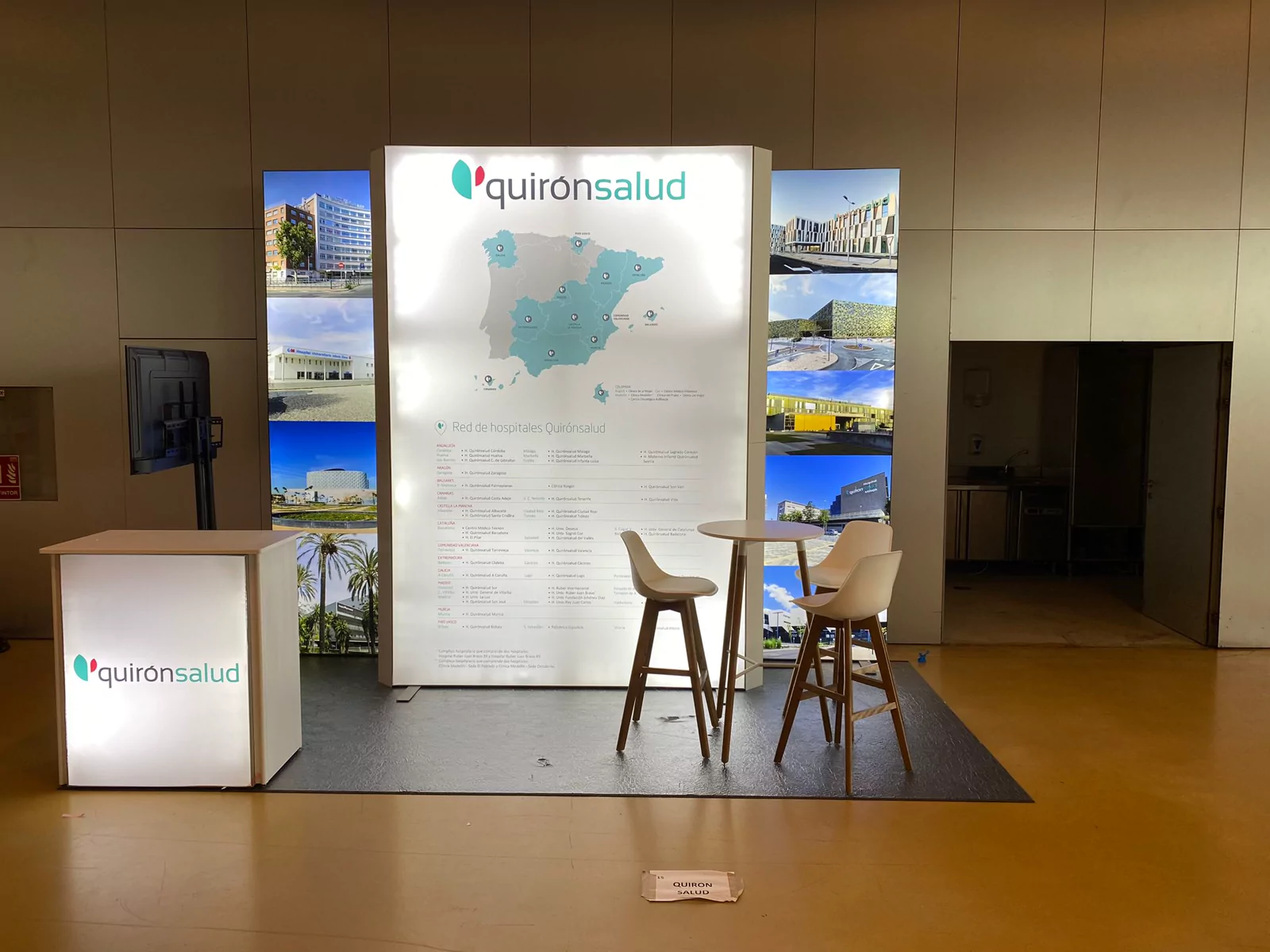Stand de Quirónsalud con mapa hospitalario retroiluminado y mostrador