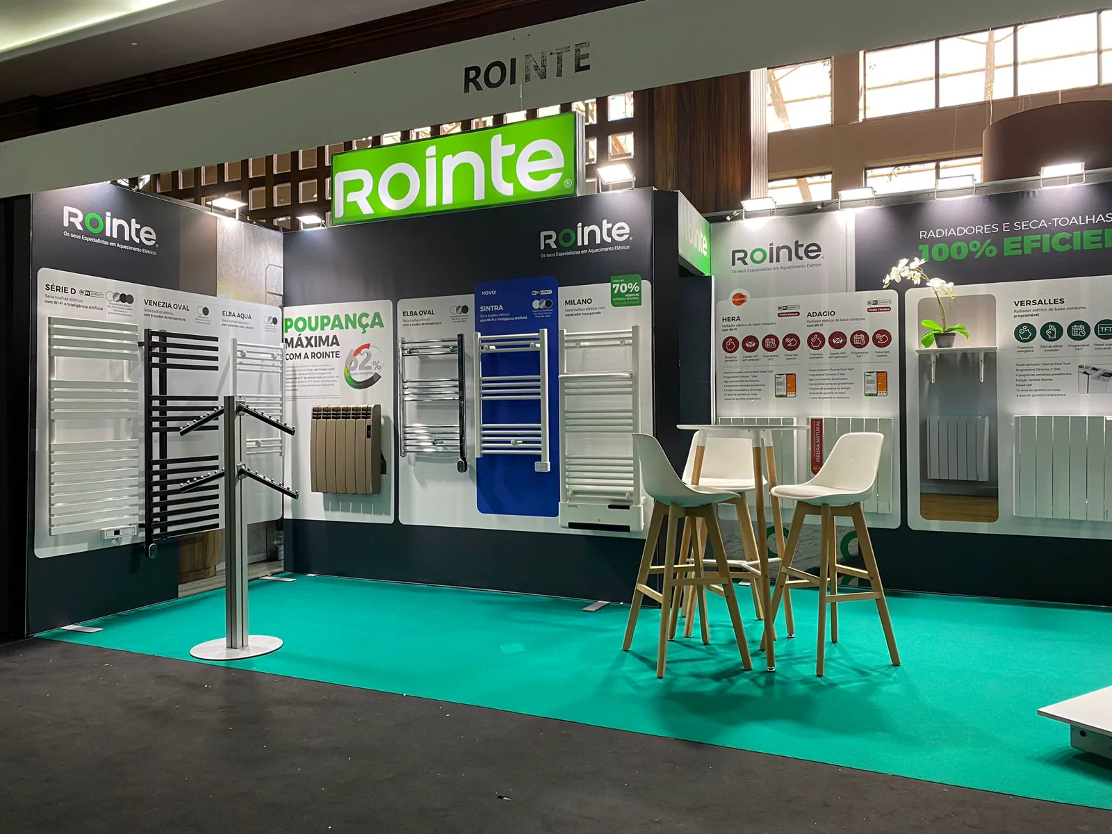 Stand de Rointe con paneles de producto, rótulos luminosos y moqueta turquesa